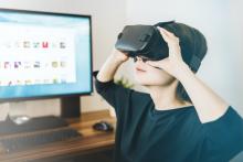 Berniukas priešais kompiuterio ekraną naudodajasi virtualia realybe